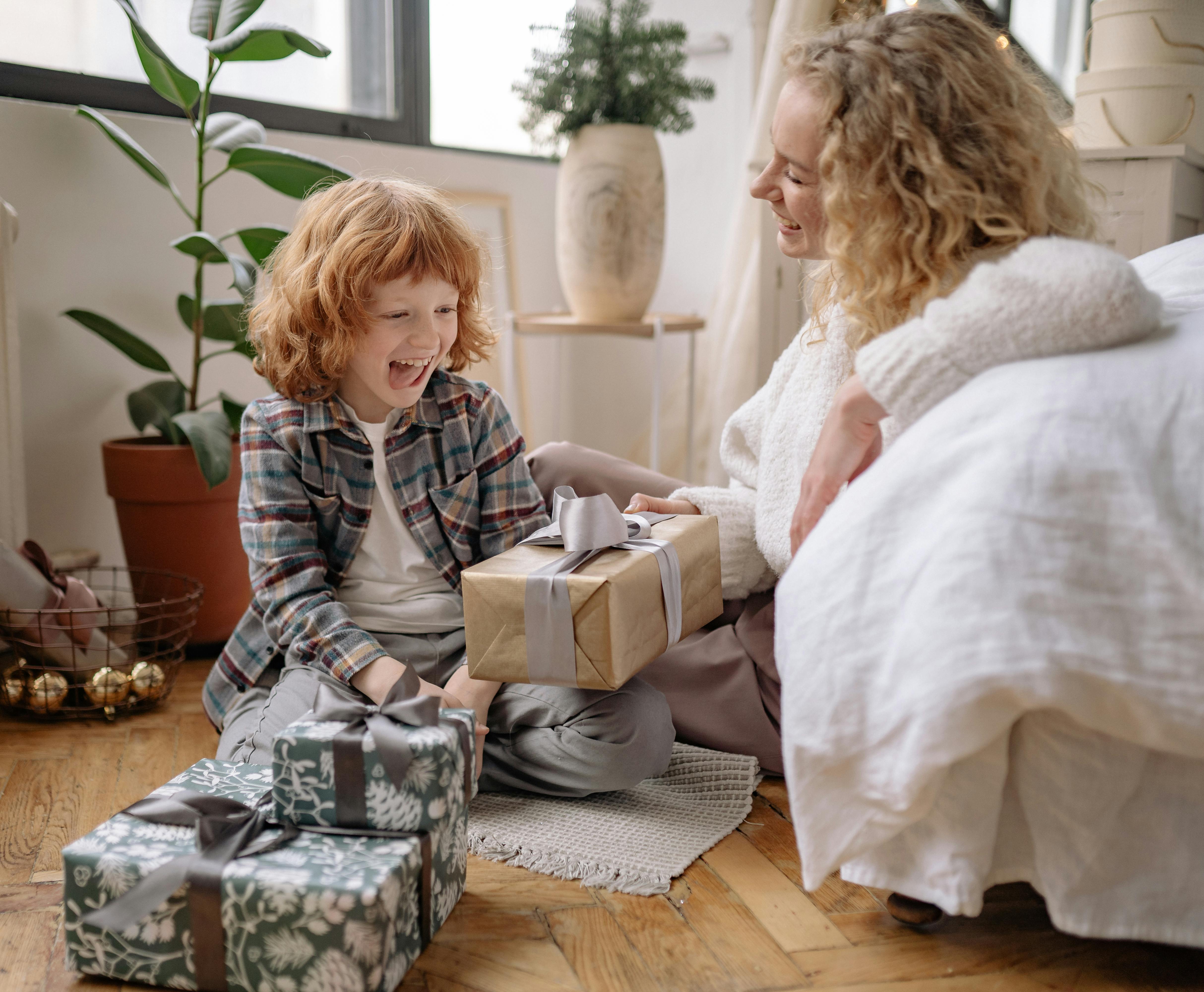 Joyful child with mother exchanging gift and learning gratitude through gentle parenting